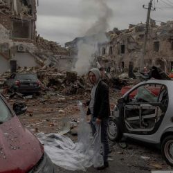 Un hombre se prepara para cubrir un coche dañado con una lona de plástico en un lugar donde se encontraban edificios residenciales gravemente dañados tras un ataque aéreo ruso a las afueras de Kiev, durante la invasión rusa de Ucrania. Un bombardeo ruso nocturno sobre Kiev mató al menos a cuatro personas, incluida una niña de 12 años, según informaron las autoridades ucranianas. | Foto:ROMAN PILIPEY / AFP