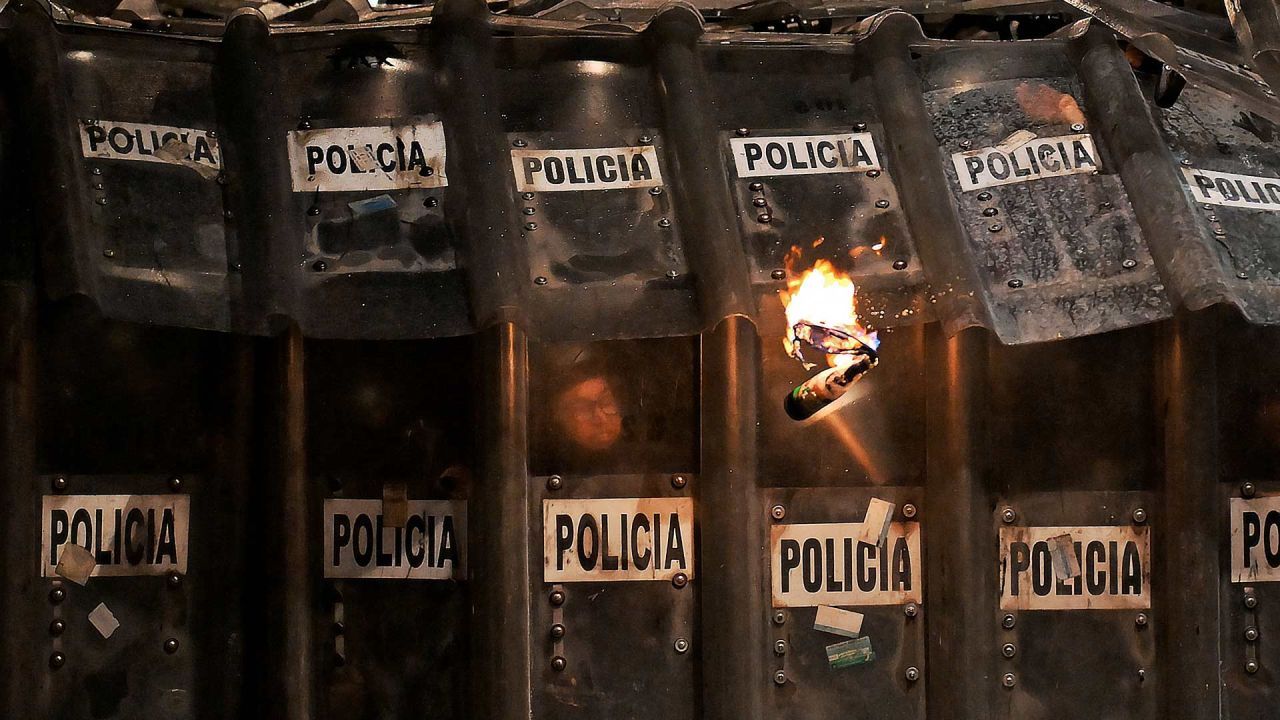 Policías antidisturbios se protegen de bombas molotov durante una protesta por el 11.º aniversario de la desaparición de 43 estudiantes de Ayotzinapa, en la Ciudad de México. En septiembre de 2014, 43 estudiantes de la Escuela Normal Rural de Ayotzinapa desaparecieron tras ser secuestrados en Iguala, Guerrero, México, en lo que se ha calificado como uno de los casos más infames de violación de derechos humanos en México. | Foto:CARL DE SOUZA / AFP