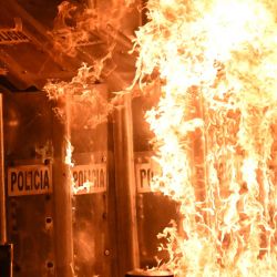 Policías antidisturbios se protegen de bombas molotov durante una protesta por el 11.º aniversario de la desaparición de 43 estudiantes de Ayotzinapa, en la Ciudad de México. En septiembre de 2014, 43 estudiantes de la Escuela Normal Rural de Ayotzinapa desaparecieron tras ser secuestrados en Iguala, Guerrero, México, en lo que se ha calificado como uno de los casos más infames de violación de derechos humanos en México. | Foto:CARL DE SOUZA / AFP