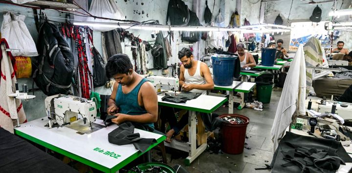 Esta fotografía muestra a sastres cosiendo ropa en una pequeña fábrica de ropa dentro de Dharavi, un asentamiento precario en Bombay.