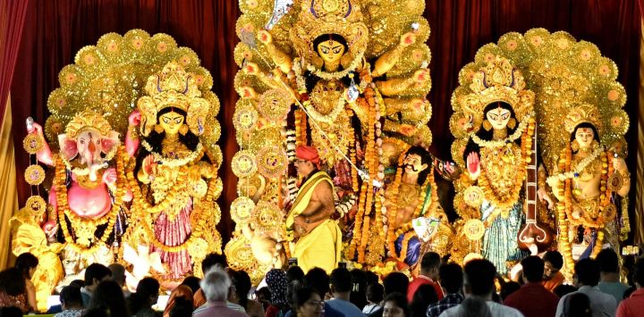 Los devotos observan a un sacerdote realizar rituales religiosos frente a un ídolo de la diosa hindú Durga en un lugar de culto temporal conocido como 'pandal' con motivo del festival Durga Puja en Bengaluru, India.