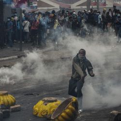 Un manifestante lanza una piedra a las fuerzas de seguridad durante una manifestación contra los repetidos cortes de agua y electricidad en Antananarivo. Manifestantes en Madagascar se congregaron para nuevas manifestaciones, un día después de que el presidente de Madagascar, Andry Rajoelina, destituyera a su gobierno en un intento por sofocar días de disturbios que han dejado 22 muertos, según la ONU. | Foto:RIJASOLO / AFP