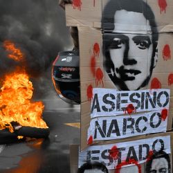 Un manifestante sostiene una pancarta con la imagen del presidente de Ecuador, Daniel Noboa, que dice "Asesino, Narcoestado", mientras participa en una protesta antigubernamental en apoyo al paro nacional convocado por la CONAIE (la mayor organización indígena de Ecuador) en Quito. La CONAIE, afirmó que Efraín Férez recibió tres disparos de soldados durante las manifestaciones del 28 de septiembre de 2025 y responsabilizó al presidente Daniel Noboa de su muerte. | Foto:RODRIGO BUENDIA / AFP