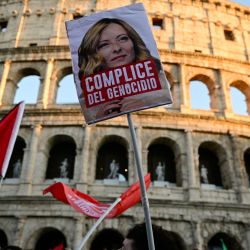 Manifestantes propalestinos sostienen una pancarta con la imagen de la primera ministra italiana, Giorgia Meloni, que dice "cómplice de genocidio" durante una marcha en apoyo a los palestinos y en protesta contra la interceptación de la Flotilla Global Sumud, cerca del Coliseo de Roma. | Foto:Tiziana Fabi / AFP