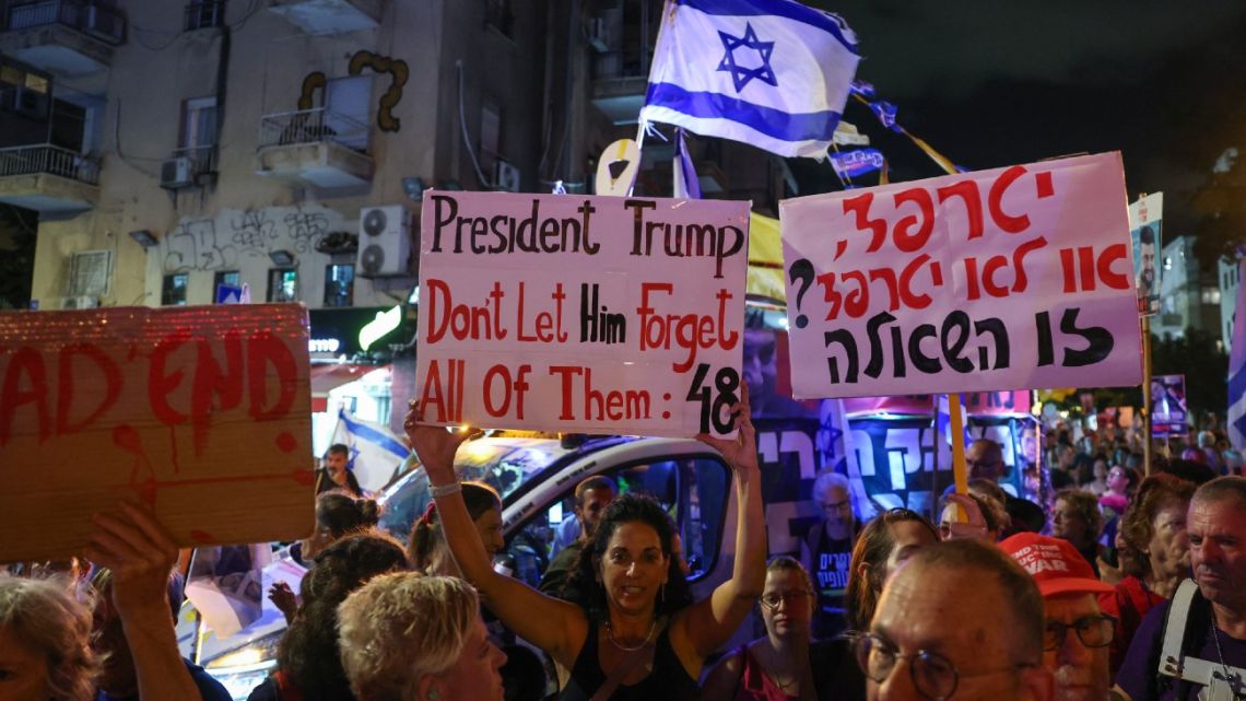 Demonstrators lift placards and flags during an anti-government protest calling for a ceasefire and for action to secure the return of Israelis held hostage in Gaza, in front of the Likud party building in Tel Aviv on September 30, 2025. 