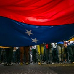 Partidarios del presidente venezolano, Nicolás Maduro, portan una bandera venezolana durante una protesta frente a la sede de las Naciones Unidas en Caracas. Venezuela declaró haber frustrado una operación de bandera falsa por parte de presuntos extremistas de derecha para colocar explosivos en la embajada de Estados Unidos en Caracas, en medio de un enfrentamiento entre ambos países por el narcotráfico. | Foto:JUAN BARRETO / AFP