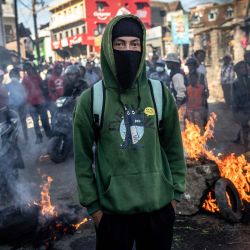 Un estudiante observa a policías malgaches frente a una barricada en llamas durante enfrentamientos con las fuerzas de seguridad en una manifestación que exige la dimisión del presidente Andry Rajoelina, en Antananarivo, Madagascar. | Foto:LUIS TATO / AFP