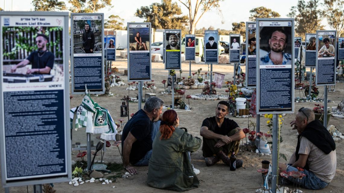 A family sits to a memorial of one of the victims of the 2023 October 7 attacks at the Nova Festival grounds in Reim, southern Israel, on the second anniversary of the attacks on October 7, 2025. 