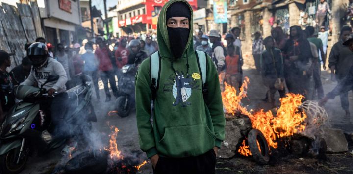 Un estudiante observa a policías malgaches frente a una barricada en llamas durante enfrentamientos con las fuerzas de seguridad en una manifestación que exige la dimisión del presidente Andry Rajoelina, en Antananarivo, Madagascar.