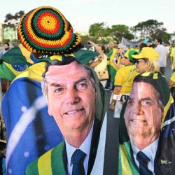 Partidarios del expresidente brasileño Jair Bolsonaro, envueltos en banderas con su imagen, participan en una marcha pidiendo amnistía para los condenados por intento de golpe de Estado en Brasilia. | Foto:EVARISTO SA / AFP