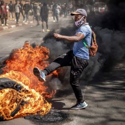 Un manifestante patea un neumático en llamas durante enfrentamientos con las fuerzas de seguridad malgaches durante una manifestación que exigía reformas constitucionales en Antananarivo, Madagascar. | Foto:LUIS TATO / AFP