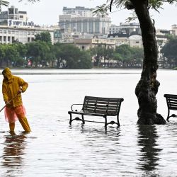 Un trabajador de drenaje barre el borde inundado del lago Hoan Kiem después de las fuertes lluvias causadas por la tormenta tropical Matmo en Hanoi, Vietnam. | Foto:Nhac NGUYEN / AFP)