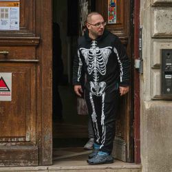 Un hombre vestido con un disfraz de esqueleto se encuentra a la entrada de una escuela primaria pública, junto al logotipo de la ciudad de París (derecha) y el logotipo de Vigipirate (izquierda), en París, el 14 de octubre de 2025.  | Foto:afp