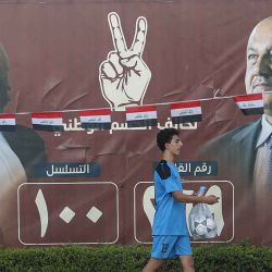 Personas circulan en sus vehículos frente a vallas electorales en una calle de Bagdad el 14 de octubre de 2025, antes de las elecciones parlamentarias del 11 de noviembre. | Foto:afp