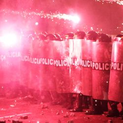 Agentes de la policía antidisturbios se protegen de los fuegos artificiales mientras se enfrentan a los manifestantes durante una protesta contra el presidente interino de Perú, José Jeri, en Lima. | Foto:CONNIE FRANCE / AFP