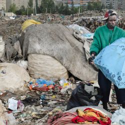 El diseñador de moda keniano, especializado en el reciclaje de telas y prendas desechadas, Morgan Azedy, hurga entre montones de prendas desechadas en un vertedero local de Nairobi. Conocido por su enfoque vanguardista en el diseño de moda, Azedy se inspira en su pasión creativa, creando una estética que desafía las convenciones y las percepciones de lo que la moda puede ser; desde intrincados tapices hasta lentejuelas brillantes, con una pasión por el denim, el cuero y los materiales reciclados como nunca antes. | Foto:TONY KARUMBA / AFP