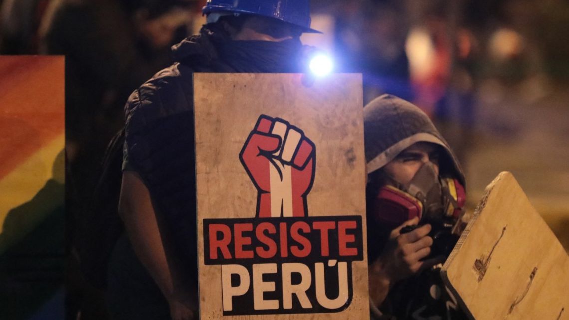 Demonstrators take cover during clashes with police after a protest against Peru's interim President Jose Jeri in Lima on October 15, 2025.