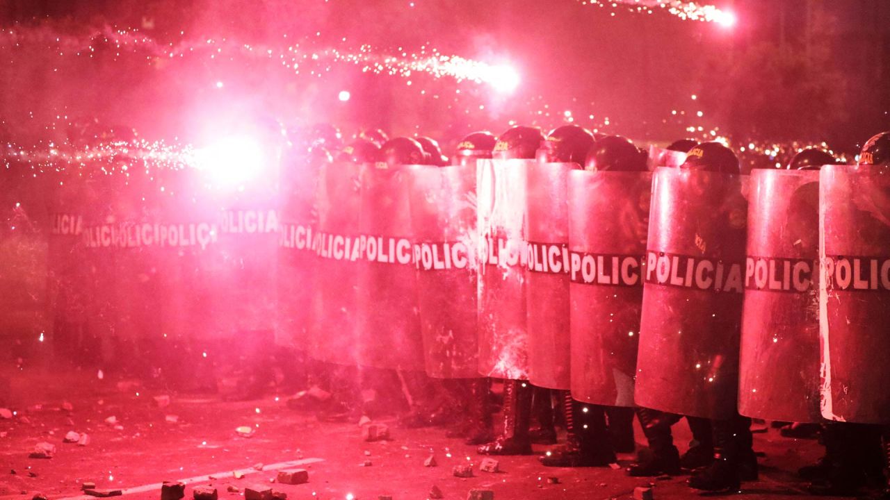 Agentes de la policía antidisturbios se protegen de los fuegos artificiales mientras se enfrentan a los manifestantes durante una protesta contra el presidente interino de Perú, José Jeri, en Lima. | Foto:CONNIE FRANCE / AFP