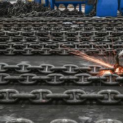 Los empleados fabrican cadenas de ancla en la línea de producción de Zhongyun Marine Equipment en Suqian, en la provincia oriental china de Jiangsu. | Foto:STR / AFP