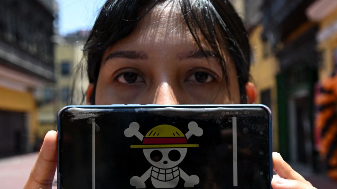 Peruvian law graduate Rosalinda,26, of the Gen Z movement, shows the One Piece manga flag on her mobile phone during an interview with AFP in Lima, on October 19, 2025. 
