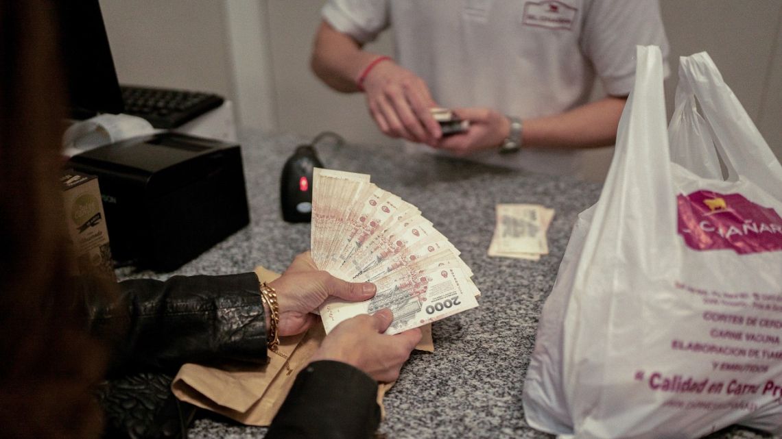 A customer pays with peso banknotes at a butcher shop in Rosario.