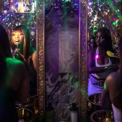 Una clienta se maquilla mientras otra se peina frente al espejo en el baño de la discoteca Zorya, en Lagos, Nigeria. | Foto:OLYMPIA DE MAISMONT / AFP