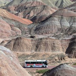 Un autobús turístico pasa por el Geoparque Nacional de Zhangye, un geoparque cuasi-nacional situado en las faldas septentrionales de las montañas Qilian, en Zhangye, provincia de Gansu, noroeste de China. | Foto:ADEK BERRY / AFP