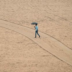Un hombre sostiene un paraguas durante las lluvias previas al ciclón Montha, en la playa Marina de Chennai. Foto de R. Satish BABU / AFP | Foto:AFP