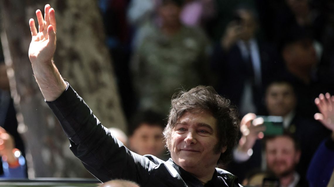 President Javier Milei waves at supporters as he arrives to vote during the national midterm legislative election, in Buenos Aires on October 26, 2025. 