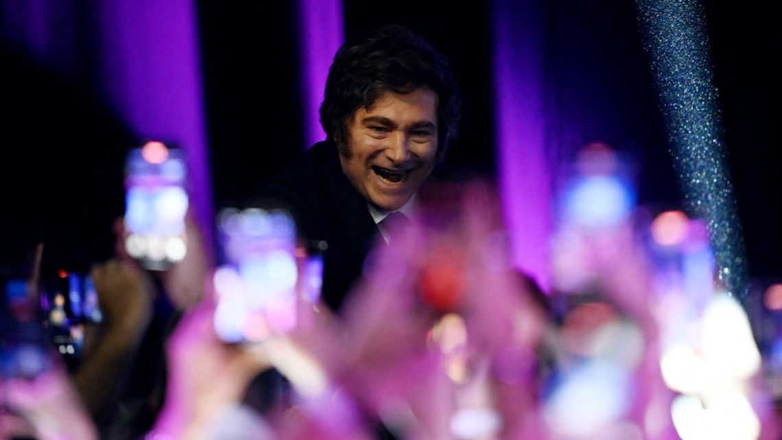 President Javier Milei greets supporters as he arrives at the ruling party's La Libertad Avanza headquarters following the results of the national midterm legislative election in Buenos Aires on October 26, 2025. 