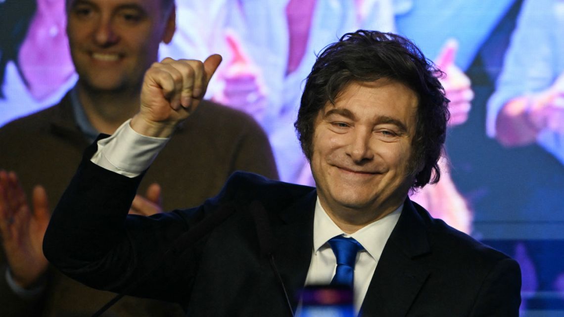 President Javier Milei waves to supporters next to the spokesperson for the Presidency Manuel Adorni at the ruling party's La Libertad Avanza headquarters following the results of the national midterm legislative election in Buenos Aires on October 26, 2025.