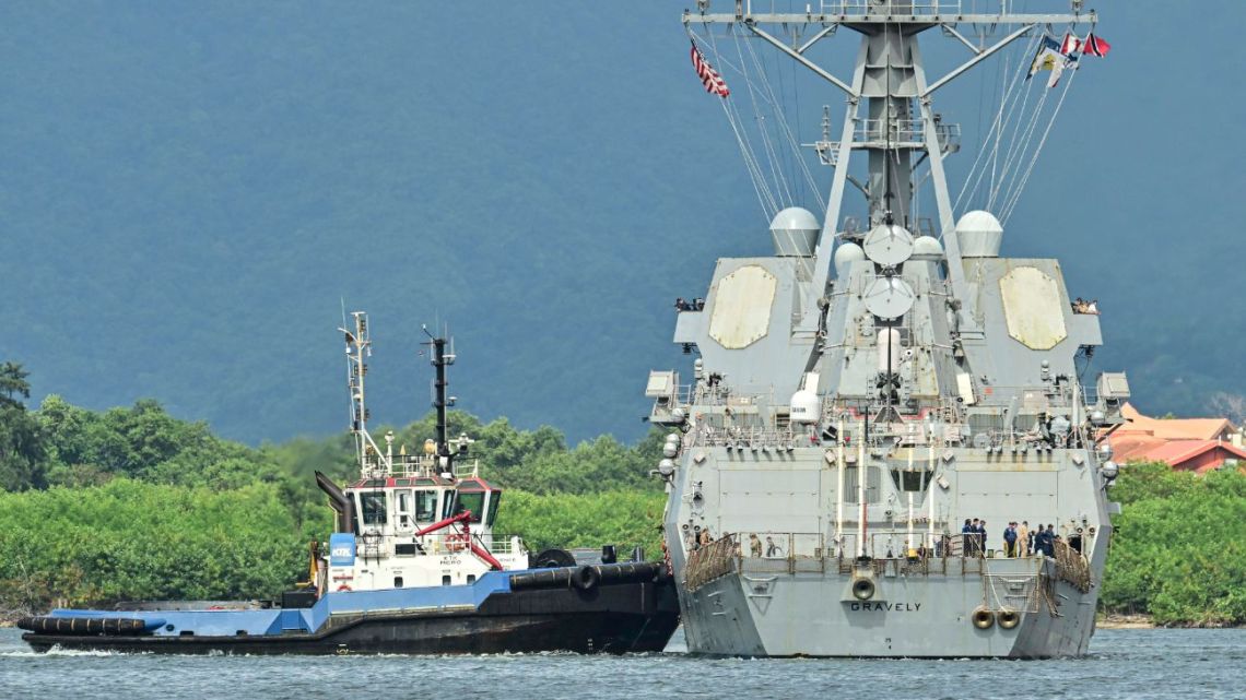 A tug boat assist the USS Gravely warship