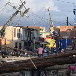 Los postes eléctricos están caídos mientras un hombre pedalea por el barrio destruido de North Street tras el paso del huracán Melissa, en Black River, Jamaica. Ricardo MAKYN / AFP | Foto:AFP