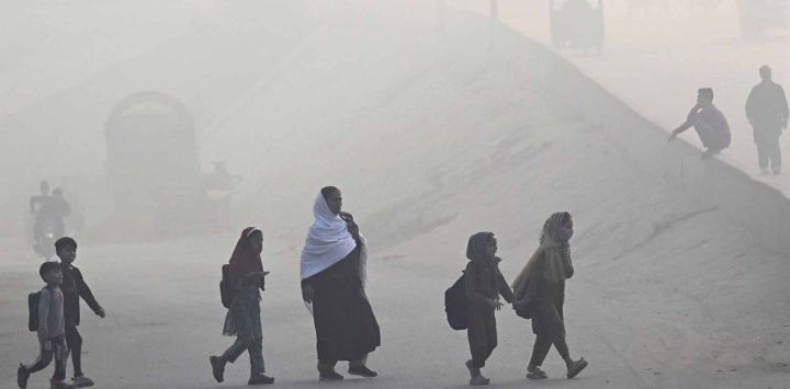 Niños escolares cruzan una calle entre la niebla en Lahore. Foto de Arif ALI / AFP