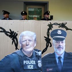 Agentes de policía se encuentran detrás de una pancarta con imágenes de (de izquierda a derecha) la presidenta de la Comisión Europea, Ursula von der Leyen; el presidente de Estados Unidos, Donald Trump; el primer ministro de Albania, Edi Rama; y la primera ministra de Italia, Giorgia Meloni, durante una protesta contra los campamentos de migrantes construidos en virtud de un acuerdo entre Roma y Tirana, frente a la embajada italiana en Albania, en Tirana. | Foto:Adnan Beci / AFP