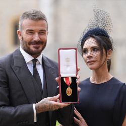 El exfutbolista inglés David Beckham posa junto a su esposa, la cantante y diseñadora de moda Victoria Beckham, con su medalla tras ser nombrado Caballero por sus servicios al deporte y a la beneficencia en una ceremonia de investidura celebrada en el Castillo de Windsor. | Foto:Andrew Matthews / POOL / AFP