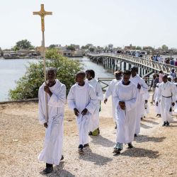 Un monaguillo porta una cruz mientras encabeza la procesión hacia el cementerio durante la festividad de Todos los Santos en la isla de Fadiouth, en Joal-Fadiouth, Senegal. | Foto:Patrick Meinhardt / AFP