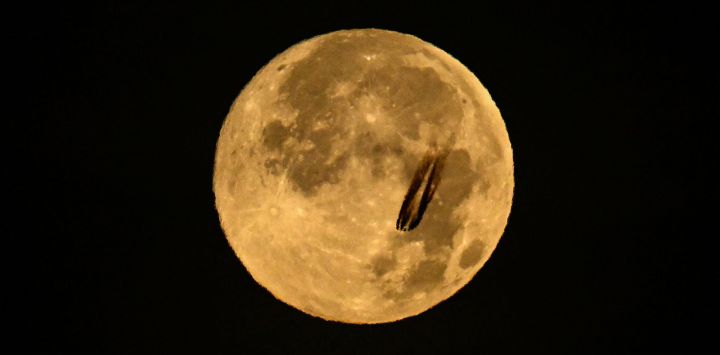 Un avión sobrevuela la luna llena de noviembre, también conocida como "Luna del Castor", sobre el distrito financiero de Fráncfort del Meno, en el oeste de Alemania.