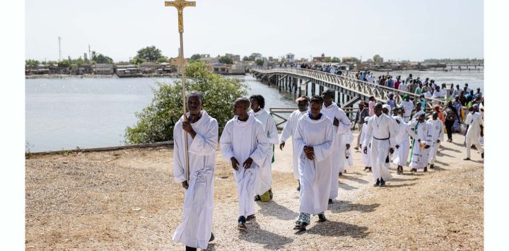 Un monaguillo porta una cruz mientras encabeza la procesión hacia el cementerio durante la festividad de Todos los Santos en la isla de Fadiouth, en Joal-Fadiouth, Senegal.