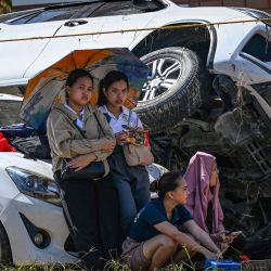 Personas descansan junto a sus autos, apilados unos sobre otros por las inundaciones provocadas por el tifón Kalmaegi, en Liloan, provincia de Cebú. El tifón Kalmaegi causó la muerte de al menos 140 personas y dejó a otras 127 desaparecidas tras provocar devastadoras inundaciones en el centro de Filipinas, según cifras oficiales. | Foto:JAM STA ROSA / AFP