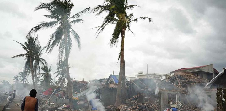 Residentes queman madera de sus casas destruidas cerca del malecón en Garchitorena, provincia de Camarines Sur, al sur de Manila. Foto de Charism SAYAT / AFP