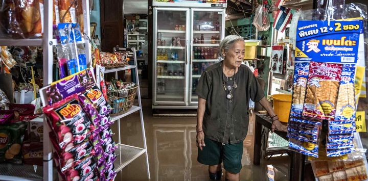 La dueña de una tienda de comestibles se encuentra dentro de su local en medio de las aguas de la inundación del río Chao Phraya en la isla Koh Kret. Foto de Chanakarn Laosarakham / AFP