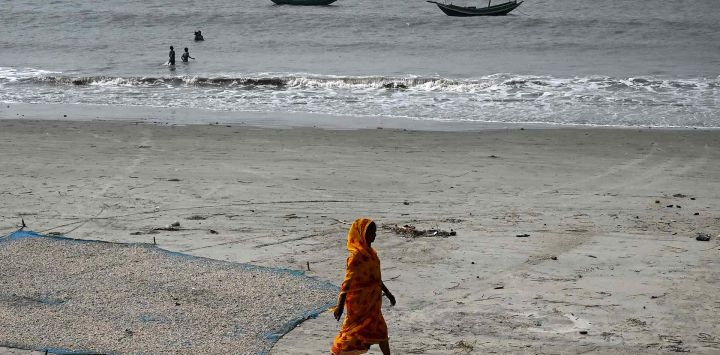 Una trabajadora pasa junto a pescados y camarones extendidos para secarse en la playa de un pueblo de pescadores en la isla de Mousuni, Bengala Occidental. Foto de DIBYANGSHU SARKAR / AFP