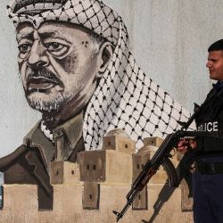 Un policía palestino monta guardia frente a una comisaría decorada con un mural del fallecido líder palestino Yasser Arafat, en Cisjordania. Foto de Hazem BADER / AFP | Foto:AFP