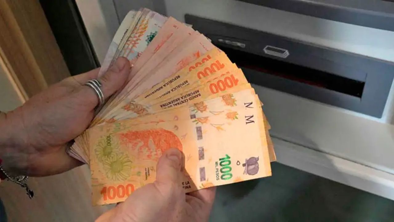 Billetes argentinos y manos retirando dinero en un cajero automático