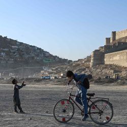 Niños afganos montan una bicicleta y vuelan una cometa cerca del lago Shuhada en Kabul. Foto de Wakil KOHSAR / AFP | Foto:AFP