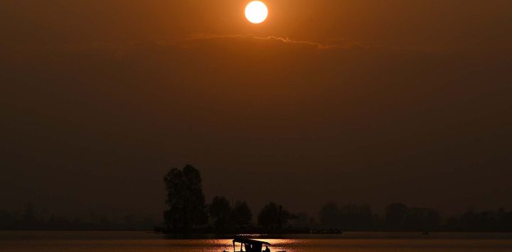 Un barquero rema su bote en el lago Dal durante el atardecer en Srinagar. Foto de Tauseef MUSTAFA / AFP