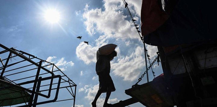Un obrero carga un saco de arroz en un camión a lo largo de un muelle en Yangon. Foto de Sai Aung MAIN / AFP