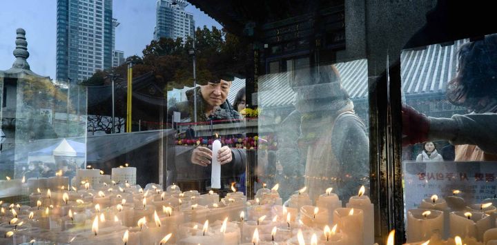 Budistas surcoreanos encienden velas en el Templo Bongeunsa mientras los estudiantes se preparan para el ingreso a la universidad Suneung, en Seúl. Foto por ANTHONY WALLACE / AFP