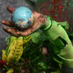 Un hombre indígena se acuesta en el suelo mientras sostiene un globo en la mano durante la "Marcha Global de Pueblos Indígenas". COP30. Brasil. Foto de Pablo PORCIUNCULA / AFP | Foto:AFP